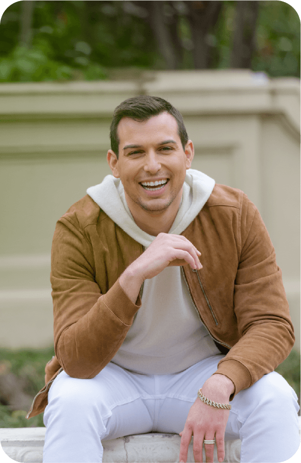 Matt sitting on a bench outside smiling at the camera